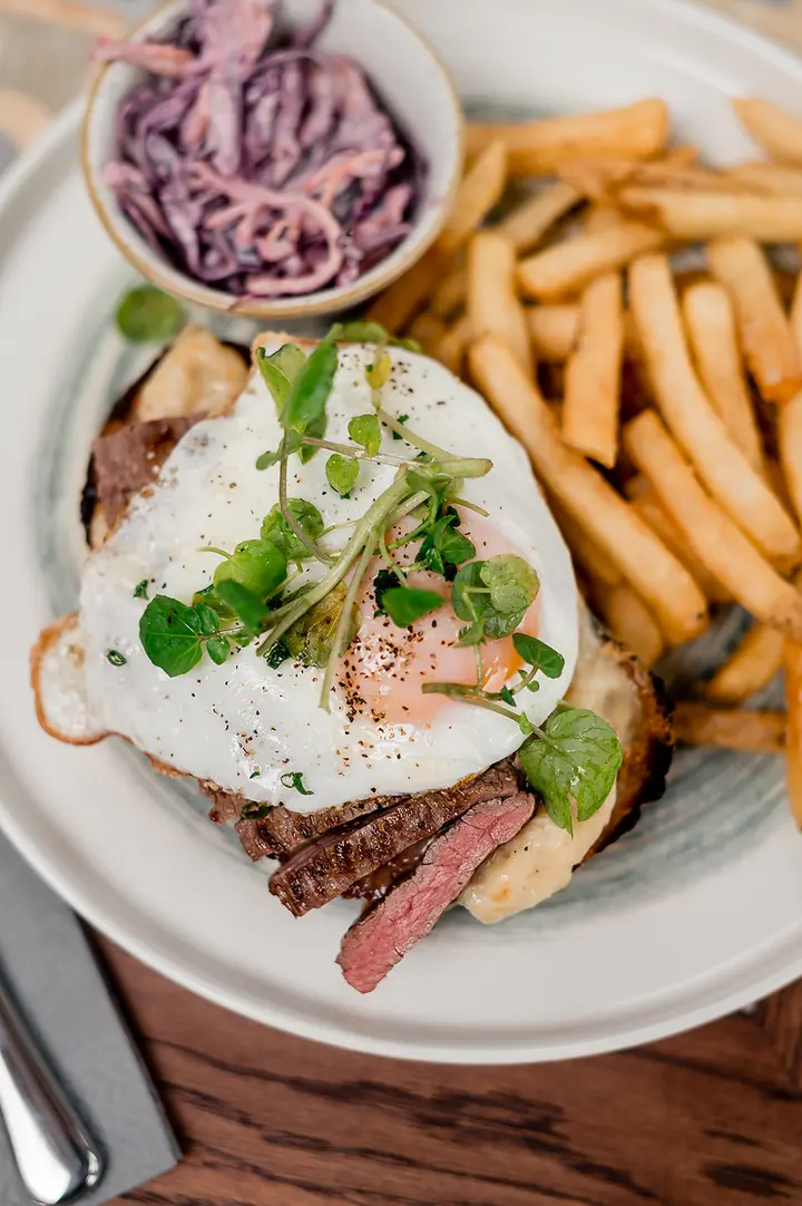 Steak with a fried egg, fries and slaw