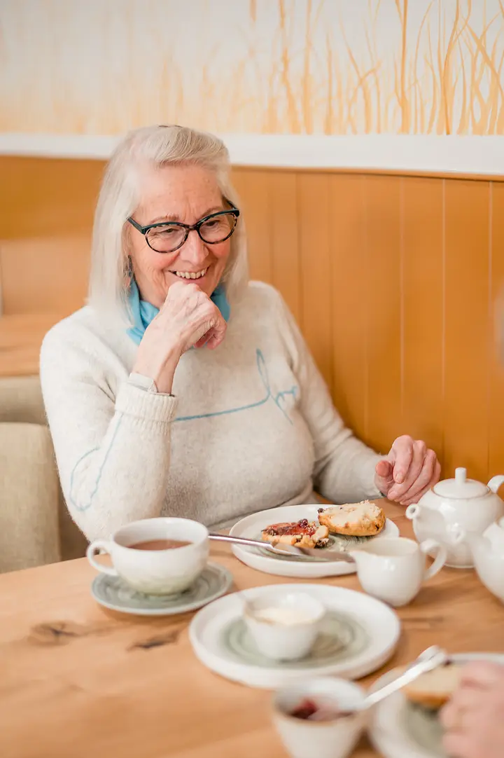 A guest laughing over tea and scones